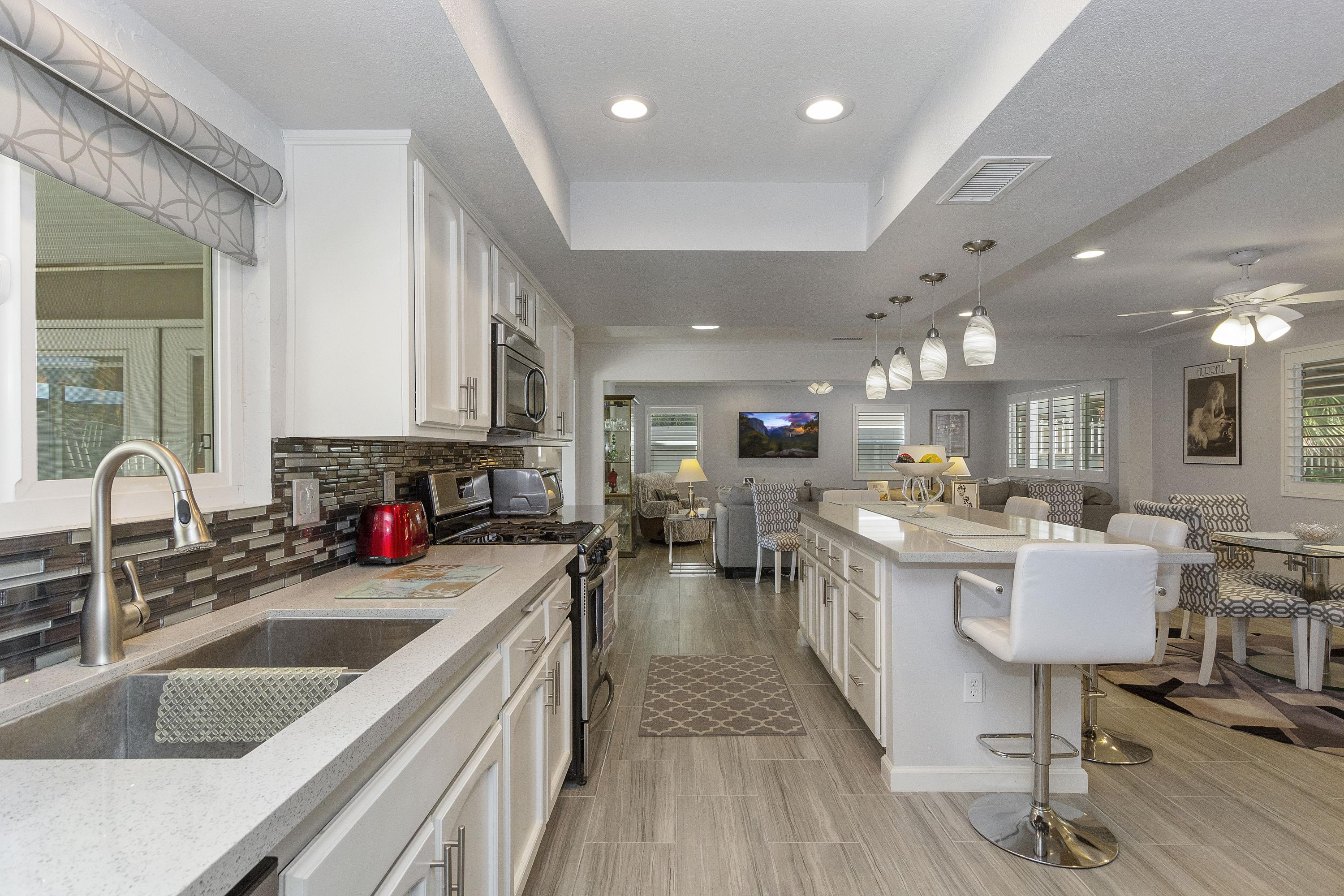 70061 Cobb Road Rancho Mirage, CA 92270 - Photo 9 of 33 a kitchen with lots of counter top space a sink appliances and cabinets