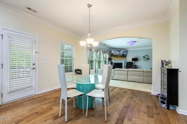 a living room with furniture and a dining table with wooden floor