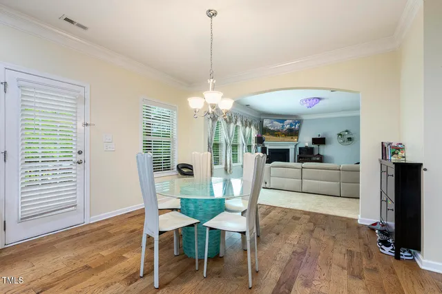 a living room with furniture and a dining table with wooden floor