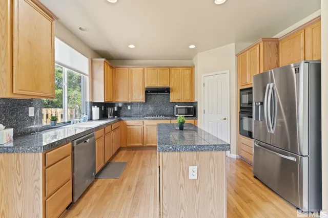 a kitchen with stainless steel appliances granite countertop a refrigerator a stove and a sink
