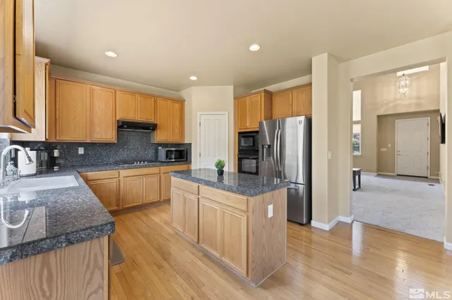 a kitchen with granite countertop a refrigerator a stove a sink a dining table and chairs