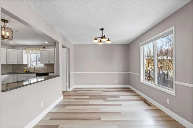 a view of a hallway with wooden floor and a kitchen