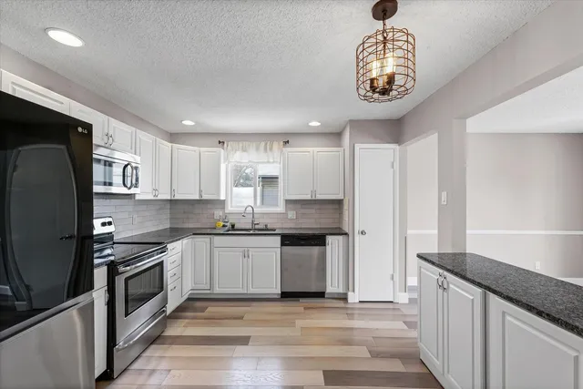 a kitchen with a sink white cabinets and stainless steel appliances