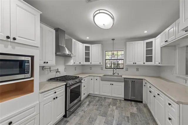 a kitchen with cabinets stainless steel appliances a sink and a window