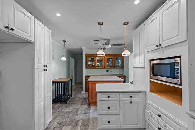 a kitchen with stainless steel appliances kitchen island granite countertop a stove a oven and a white cabinets with wooden floor