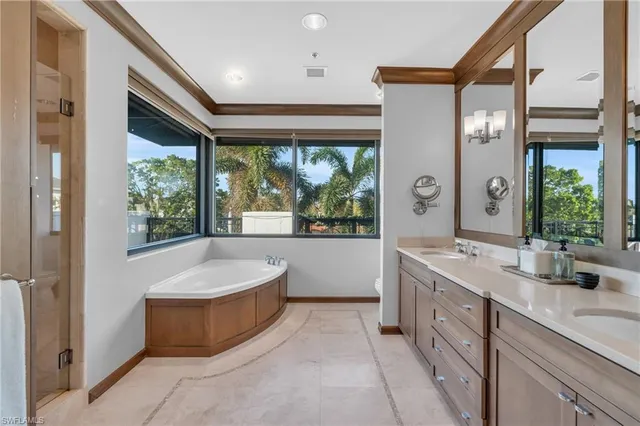 a spacious bathroom with a double vanity sink a large mirror a bathtub and window