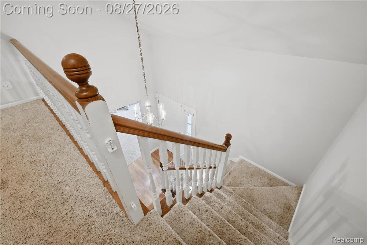 10100 Springtime Circle Clarkston, MI 48348 - Photo 41 of 73 Staircase with carpeted treads and risers, featuring a wooden handrail and white balusters
