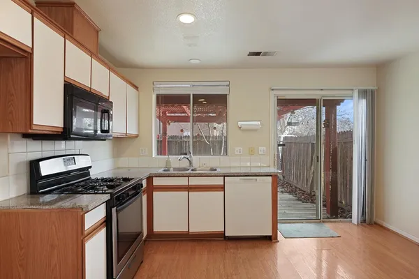 a kitchen with stainless steel appliances granite countertop a stove a sink and a microwave