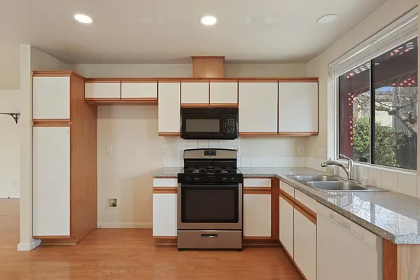 a kitchen with granite countertop a stove a sink and a refrigerator