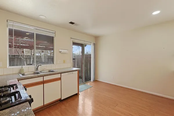 a large kitchen with a sink and wooden floor