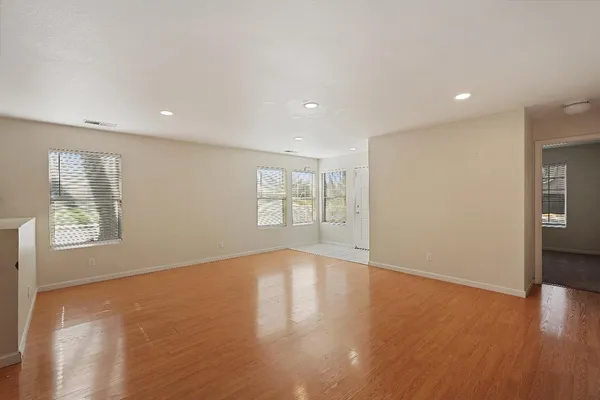 a view of an empty room with wooden floor and a window