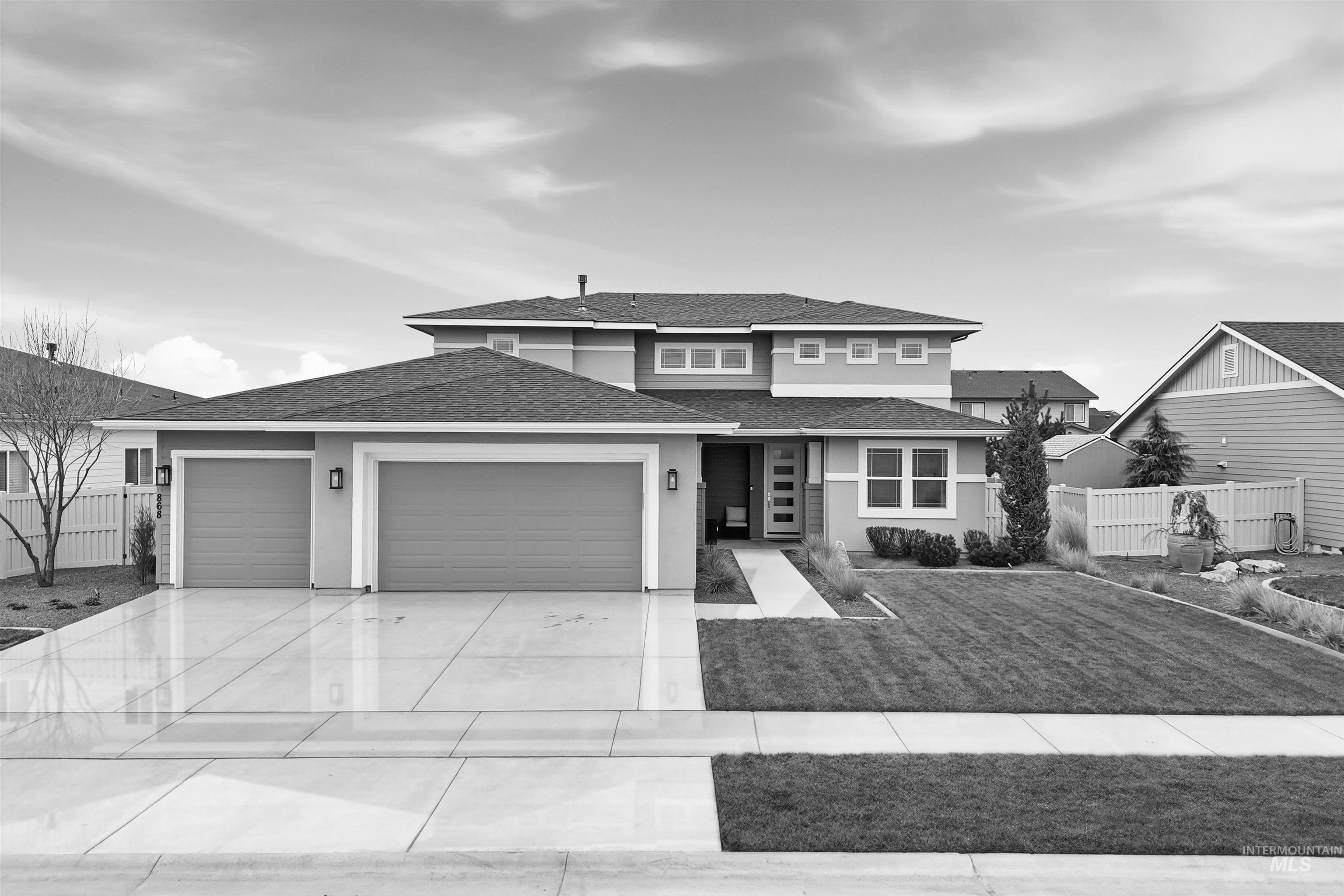 868 West Grassland Street Middleton, ID 83644 - Photo 18 of 39 Contemporary architectural exterior with a multi-level roofline, prominent two-car garage, manicured lawn, and a stone-edged planting bed
