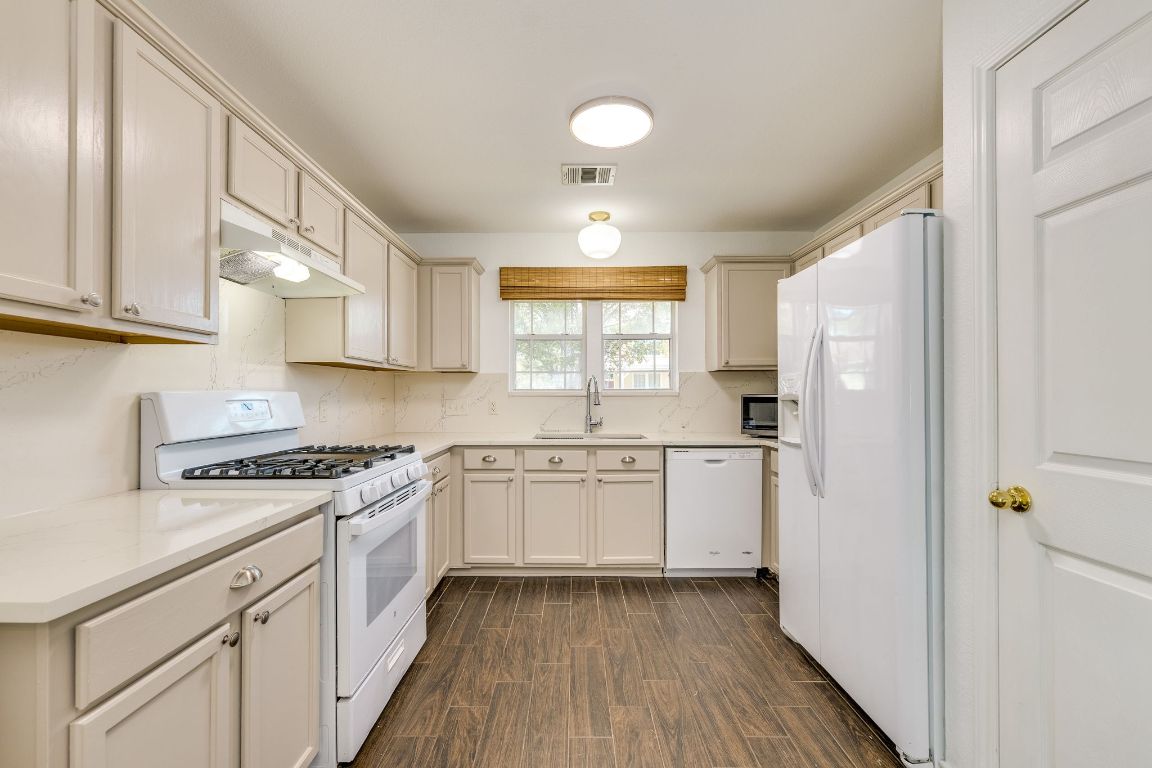 356 Wetzel Kyle, TX 78640 - Photo 4 of 24 a kitchen with granite countertop white cabinets and white appliances