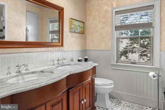 a bathroom with a granite countertop sink a toilet and a mirror