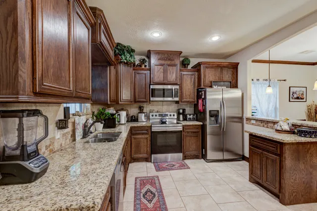 a kitchen with stainless steel appliances granite countertop a refrigerator a stove a sink and dishwasher