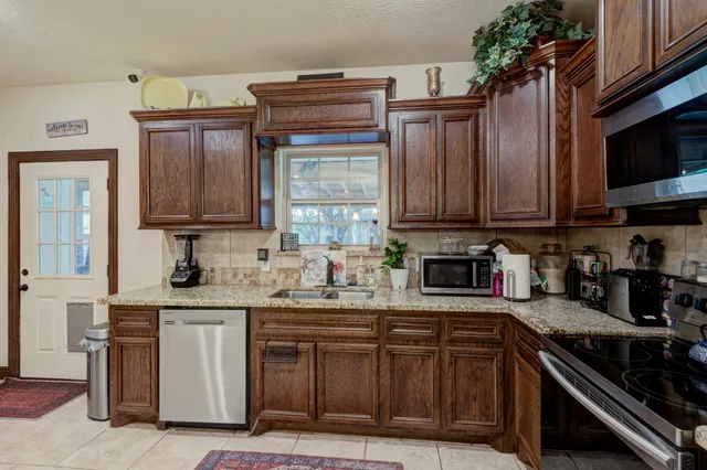 a kitchen with stainless steel appliances granite countertop a stove top oven a sink dishwasher and cabinets with wooden floor