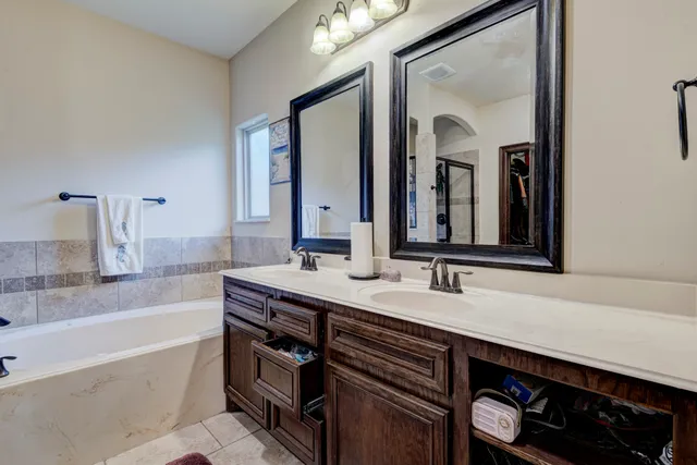 a bathroom with a bathtub a double vanity sink and a mirror