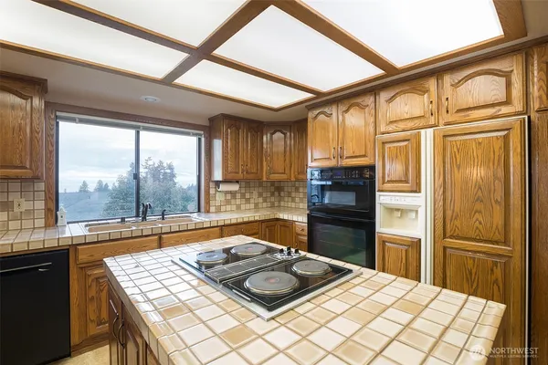 a kitchen with a refrigerator a stove top oven cabinetry a sink and a large window