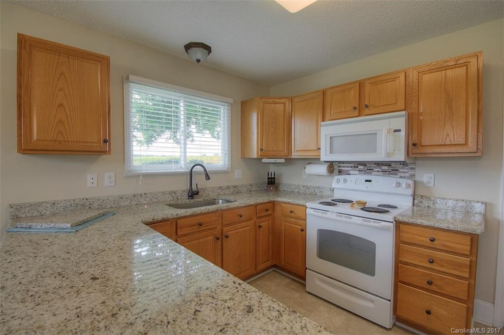 6114 Olive Branch Road Wingate, NC 28174 - Photo 15 of 24 a kitchen with granite countertop white cabinets sink and window