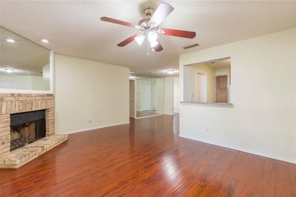 a view of an empty room with wooden floor and a fireplace