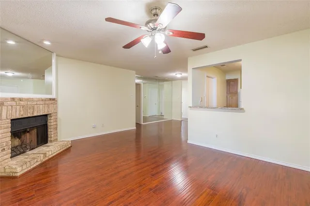 a view of an empty room with wooden floor and a fireplace