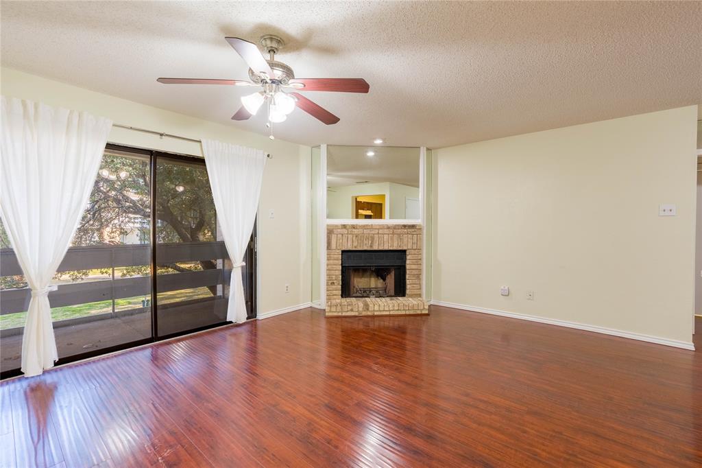 5840 Spring Valley Road, Unit 212 Dallas, TX 75254 - Photo 15 of 32 a view of an empty room with wooden floor fireplace and a window