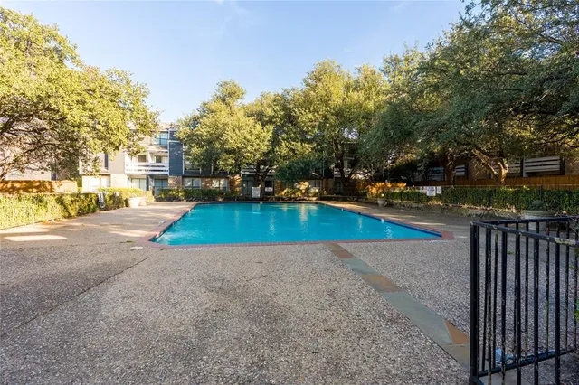 a view of a swimming pool with a yard and large trees