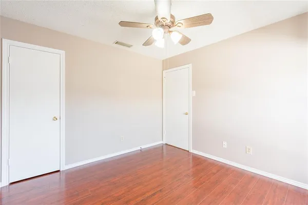 an empty room with wooden floor and fan