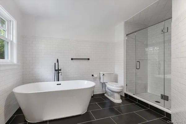 a bathroom with a white tub shower and a toilet