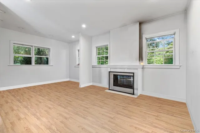 an empty room with windows and fireplace