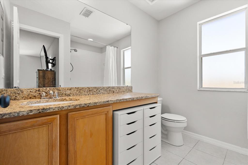 122 Capri Drive Davenport, FL 33897 - Photo 19 of 35 a bathroom with a granite countertop toilet a sink and a mirror