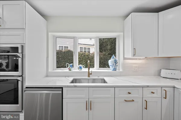 a kitchen with stainless steel appliances granite countertop white cabinets and a window