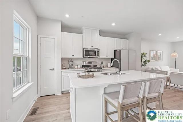 a kitchen with kitchen island granite countertop a stove a sink a refrigerator and white cabinets with wooden floor