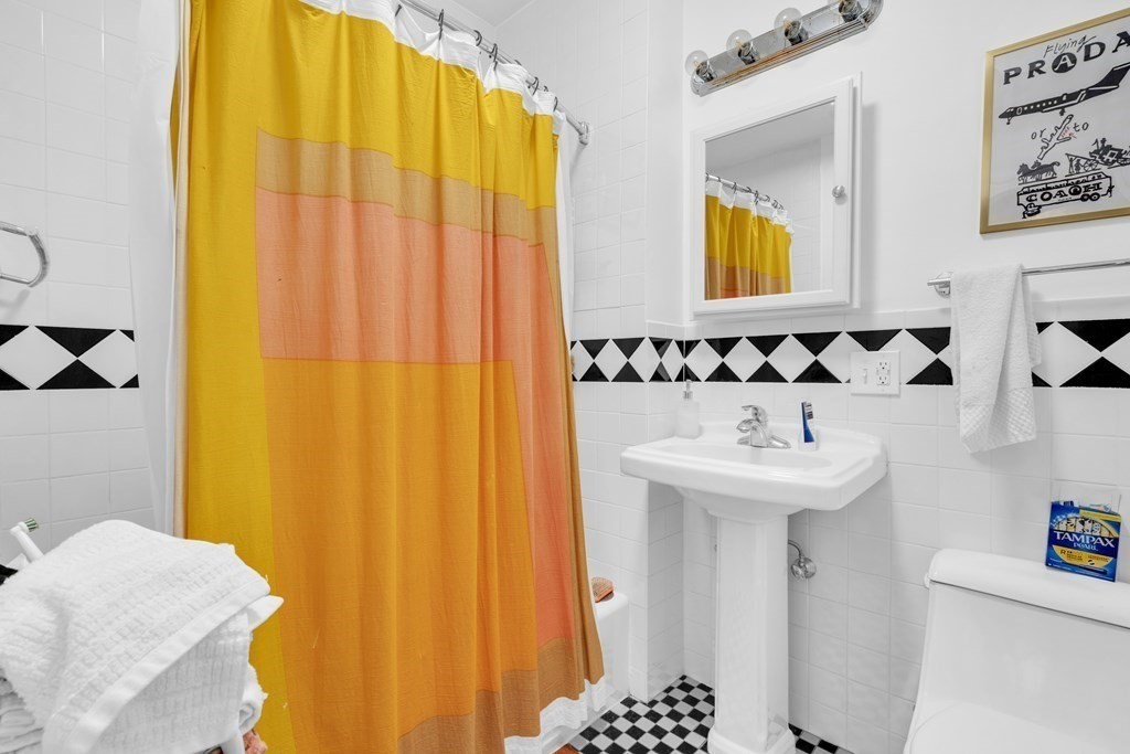 493-495 East 7th Street Boston, MA 02127 - Photo 17 of 22 a bathroom with a sink a mirror and a shower curtain