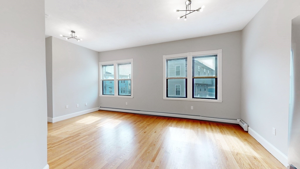 181 Highland Street, Unit 1 Boston, MA 02119 - Photo 3 of 11 an empty room with wooden floor and windows