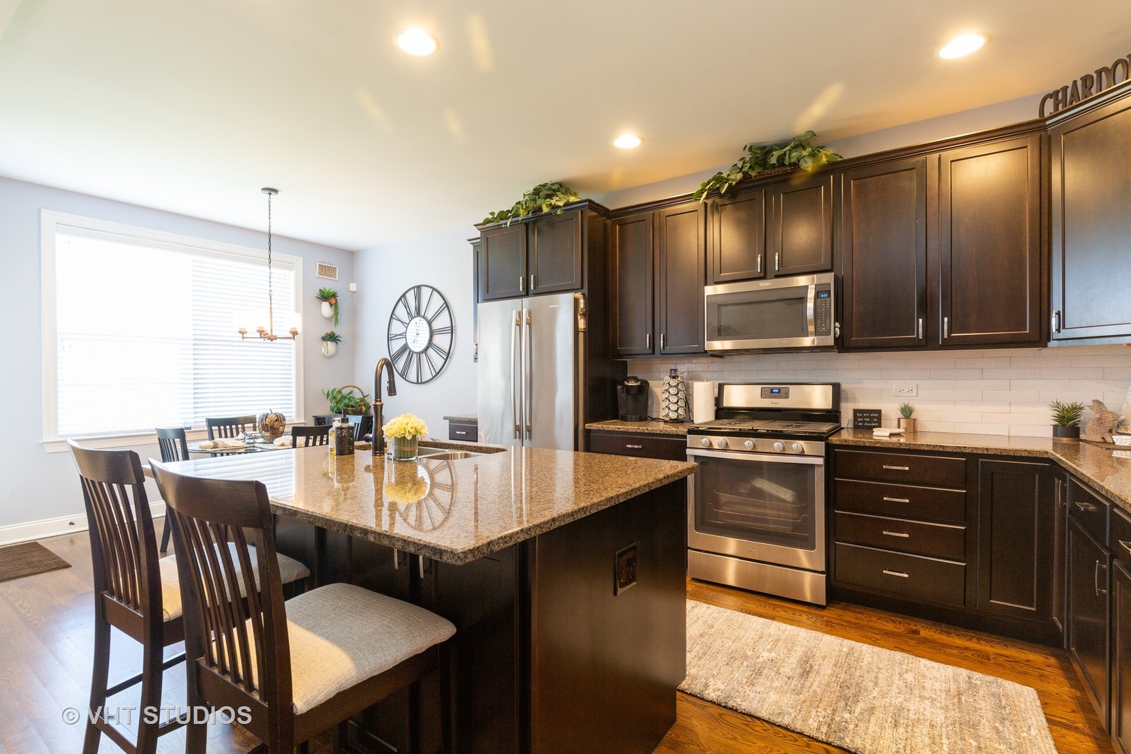 1175 Falcon Ridge Drive, Unit 1175 Elgin, IL 60124 - Photo 5 of 17 a large kitchen with granite countertop a stove top oven a sink dishwasher a dining table and chairs with wooden floor