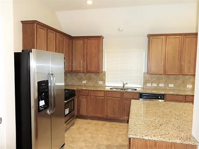 a kitchen with stainless steel appliances granite countertop a refrigerator and a sink