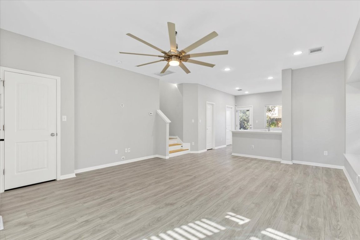4524 Kind Way, Unit 257 Austin, TX 78725 - Photo 4 of 16 Unfurnished living room with ceiling fan, stairs, light wood-style flooring, and recessed lighting