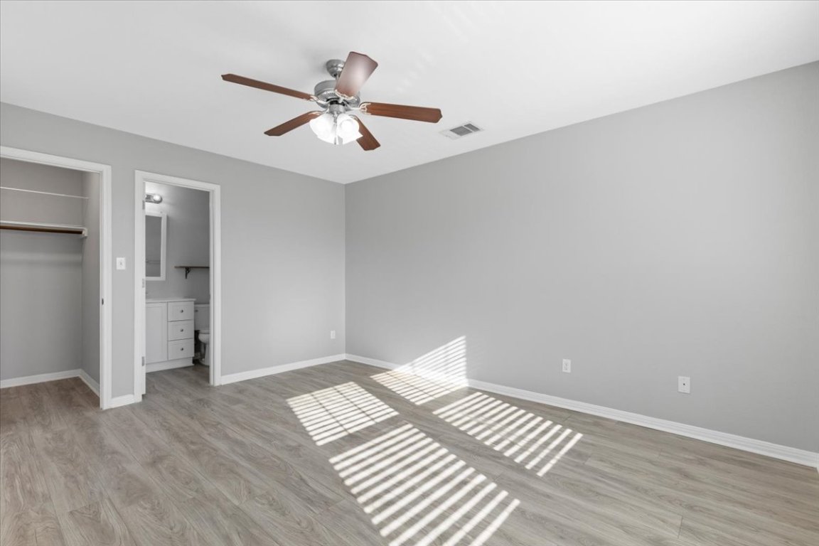 4524 Kind Way, Unit 257 Austin, TX 78725 - Photo 6 of 16 Unfurnished bedroom featuring light wood finished floors, a walk in closet, and ceiling fan