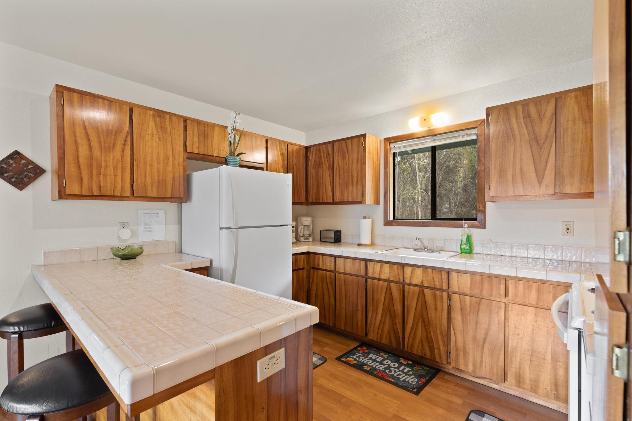 99-1817 Painiu Loop Volcano, HI 96785 - Photo 9 of 30 a kitchen with a sink a refrigerator and cabinets