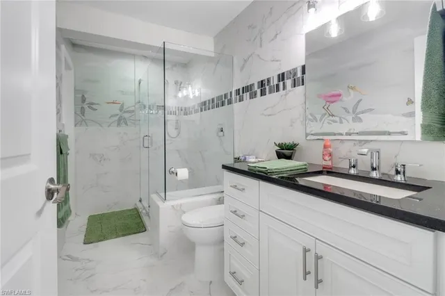 a bathroom with a granite countertop sink a toilet a mirror and shower