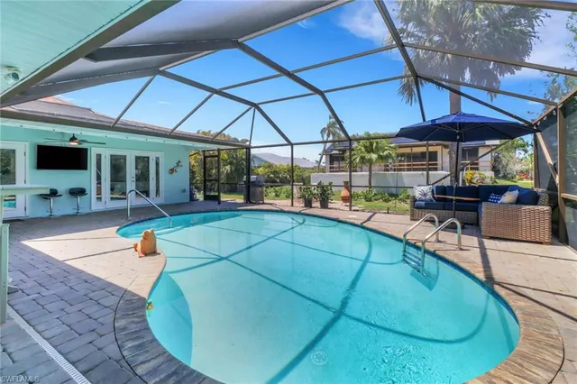 an outdoor sitting area with a table and chairs under an umbrella