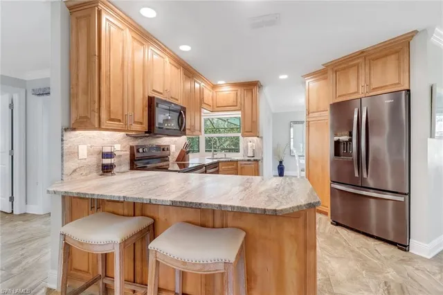 a kitchen with stainless steel appliances granite countertop a stove a refrigerator a sink a dining table and chairs