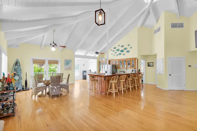 a dining hall with stainless steel appliances granite countertop a stove top oven a dining table and chairs with wooden floor