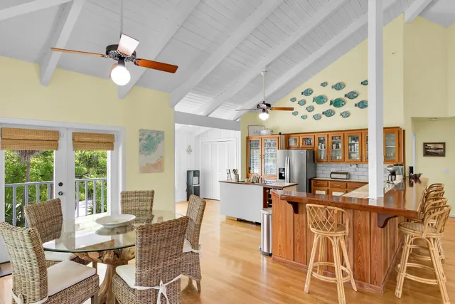 a dining hall with stainless steel appliances granite countertop a stove a refrigerator a dining table and chairs with wooden floor