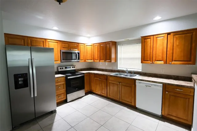 a kitchen with granite countertop stainless steel appliances cabinets a sink and a large window