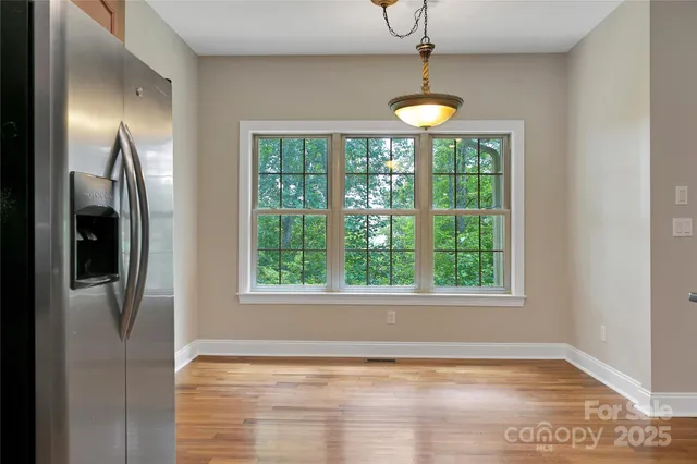 a view of an empty room with window and chandelier fan