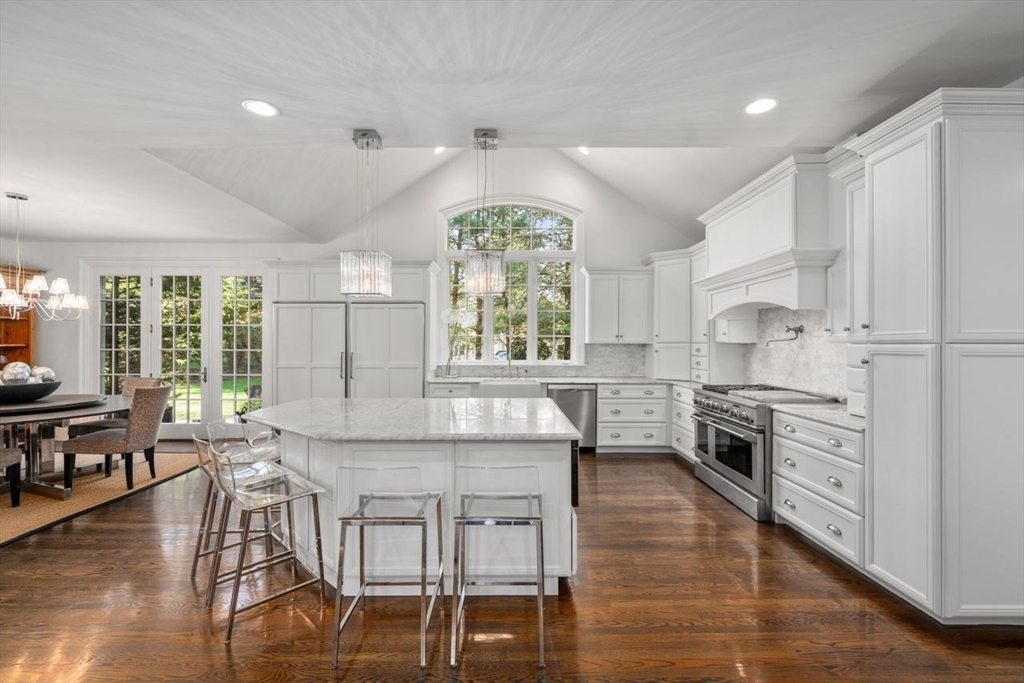 22 Plymouth Road Wellesley, MA 02481 - Photo 10 of 37 a kitchen with stainless steel appliances granite countertop a stove top oven a sink a dining table and chairs with wooden floor