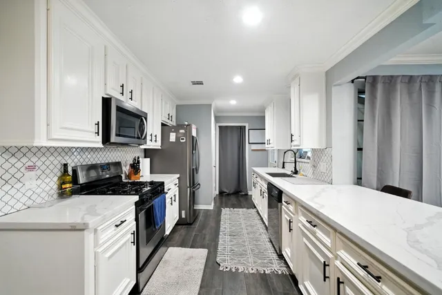 a kitchen with stainless steel appliances a sink stove refrigerator and cabinets
