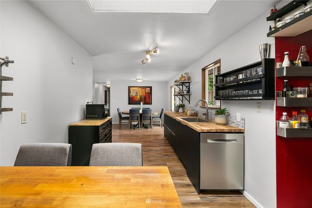 a kitchen with stainless steel appliances kitchen island granite countertop a sink dishwasher stove and couches with wooden floor